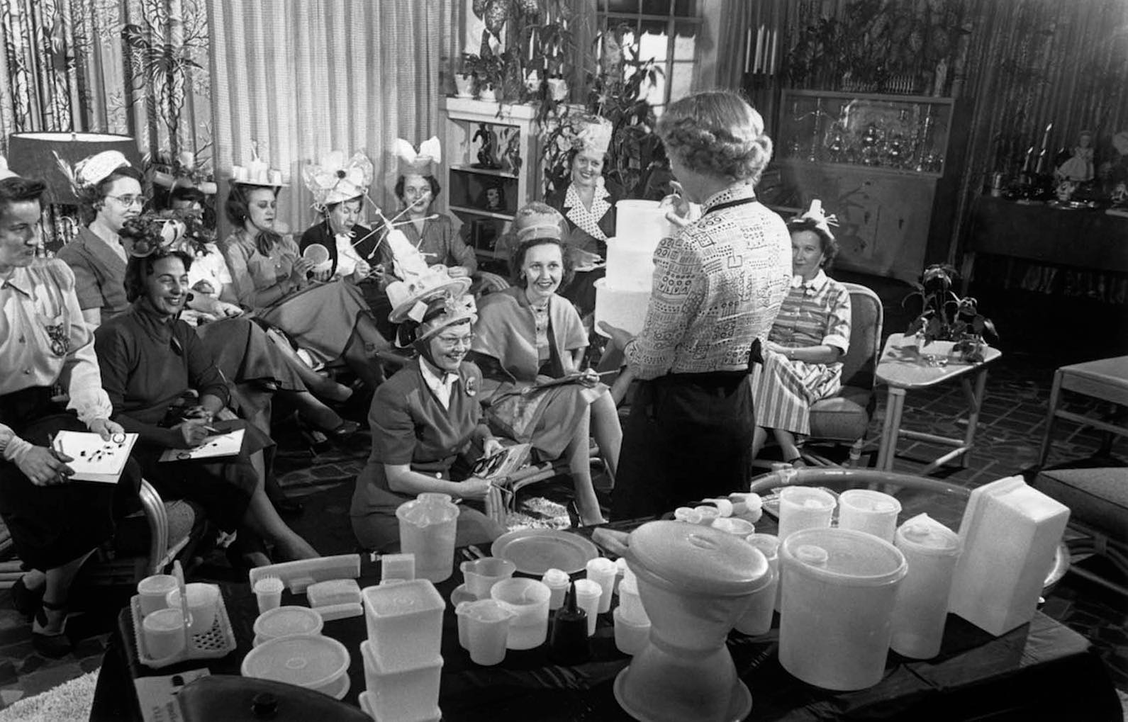 A Tupperware party in full swing in the 1950s. A table in the foreground displays a range of the company’s products.