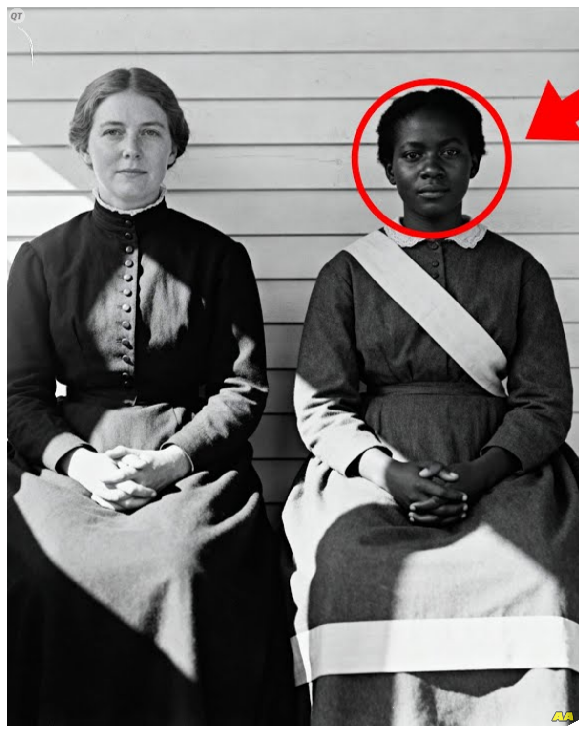 This 1867 Photo of Two Women Looks Peaceful Until You Notice The Ribbon  This 1867 photo of two women looks peaceful until you notice the ribbon.  It hung on the wall of a county historical society in Clarksville, Tennessee for almost 30 years.  Visitors would pause, smile at the image of two women sitting together in what looked like friendship.  Most moved on within seconds, but Sarah Chen, the society’s photo archivist, had stopped being able to walk past it.  She stood in the small conservation lab on a Tuesday morning in March, the photograph now flat on the light box in front of her.  12 years of cataloging Civil War era images had taught her to see past the obvious composition, and something in this image had been bothering her for weeks.  The photograph showed two women seated side by side on what appeared to be a narrow porch bench.  Their posture was formal, but their hands were clasped together, fingers intertwined in a gesture that suggested intimacy or solidarity.  The woman on the left was white, perhaps in her 30s, with dark hair parted severely down the middle and pulled back.  She wore a high-necked dress with small buttons running up to her throat.  The woman on the right was black, younger, maybe mid-20s, with a slight forward lean, as if she had been caught mid-breath………….
